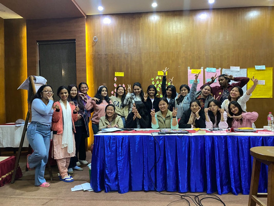 Group photo of participants of the event, smiling at the camera, pointing their fingers up in a peace sign 